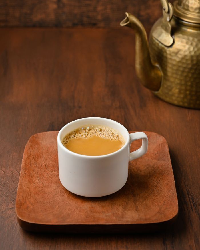 Enjoy a traditional Indian chai served on a wooden platter with a vintage brass kettle.