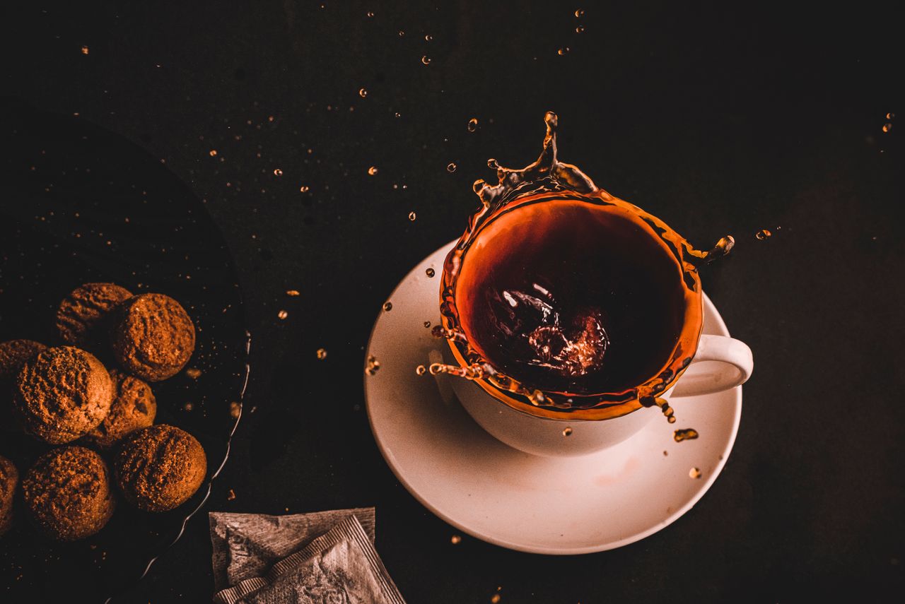 Capture of a tea splash in a cup with cookies on the side, creating a dynamic scene.