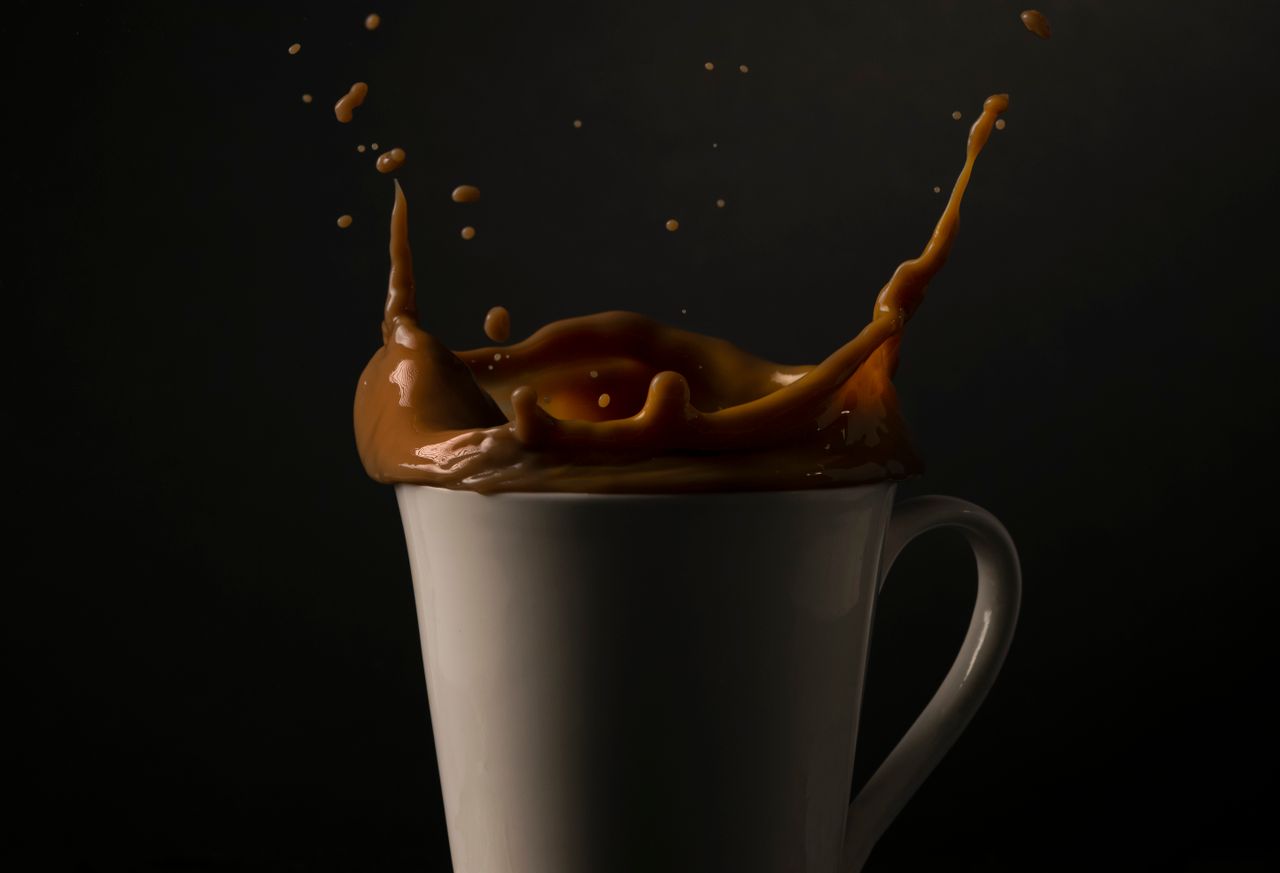 Captivating shot of coffee splash in a white cup against a dark background, emphasizing motion and texture.
